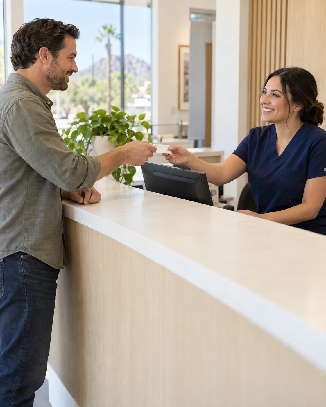 Patient handing his Cigna dental insurance card to the front desk at Diamondback Dentistry in Phoenix